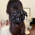 Elegante fermaglio per capelli con fiocco floreale nero indossato da una donna in un caffè - Nero Floreale