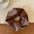 Detail van bruine gestreepte zijden scrunchie met zilveren kralen op beige geweven mat - Bruine strepen