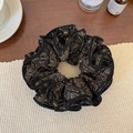 Dettaglio dell'elastico per capelli nero con stampa paisley su un tavolo di legno - Nero Floreale a Quattro Strati