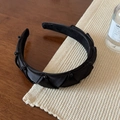 Macro detail of black satin twisted headband with elegant bead accents and non-slip lining - Satin