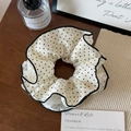 Gros plan d'un grand chouchou à pois noirs et blancs avec des détails en dentelle - Beige à Pois