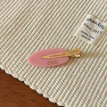 Nahaufnahme der rosa Haarspange mit goldenem Entenschnabel-Clip auf gewebtem Stoff - Rosa
