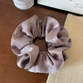 Close-up of elegant satin scrunchie in dusty purple with a gold brand logo tag - Lotus Root Purple