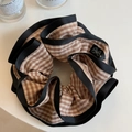 Close-up of oversized brown gingham scrunchie with black trim and elegant bow logo - Brown Stripes