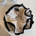 Detailed view of striped large hair scrunchie with black trim on a minimalist white desk - Beige Striped