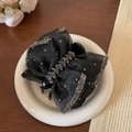 Détail de la pince à cheveux noeud en tulle noir avec paillettes argentées sur céramique - Style Épi de Blé
