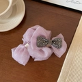 Detail view of purple organza bow hair claw clip with rhinestones on a wooden desk - 13cm / Pink