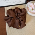 Detailed close-up of dark brown satin scrunchie with elegant golden logo charm - Dark Coffee