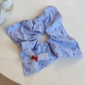 Détail d'un chouchou à carreaux bleus avec nœud en dentelle blanche et broderie - Carré de tissu bleu