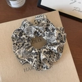 Detailopname van zwart-witte paisley haarelastiekje op een decoratieve boekomslag - Crème Bloemenprint