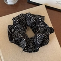 Detailweergave van grote zwarte scrunchie met wit paisley patroon op textuurstof - Zwart Bedrukt