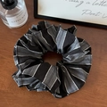 Dettaglio di un grande elastico a righe nere e grigie con etichetta FASHION su fondo legno - Nero