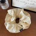 Dettaglio di un elastico a righe beige con etichetta FASHION nera su tavolo di legno - Bianco Sporco