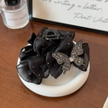 Détail de la pince à cheveux nœud noir élégante avec cristaux sur un plateau blanc - Noir 13cm