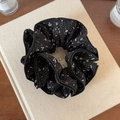 Detailopname van een zwarte vierlaagse scrunchie met witte bloemenprint op boek - Zwart Bloemen