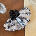 Gros plan détaillé du chouchou en satin à imprimé floral avec un design élégant de pompon - Style Jupe à Imprimé Encre Noir et Blanc
