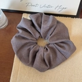 Close-up of oversized taupe fabric scrunchie with fine linen-like weave and rich folds - Gray