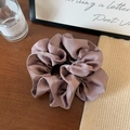 Close-up of a premium pleated satin scrunchie in coffee brown on a wooden desk - Fuschia
