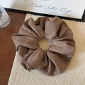 Detailed close-up of a large coffee brown fabric scrunchie with elegant pleated texture - Brown