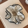 Detailopname van een bloemen scrunchie met zwarte patronen en contrasterende rand - Crèmekleurig Bloemig