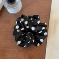 Detail shot of black chiffon scrunchie with white polka dots on a wooden surface - Black