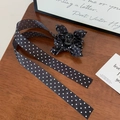 Primer plano de una pinza para el pelo con lazo de lunares negros y borlas largas elegantes - Pinza para el Pelo Lunares Negros