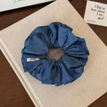 Detail of dark blue denim scrunchie with soft fabric texture and decorative white label - Double Layer Scrunchie
