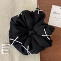 Dettaglio dell'elastico per capelli nero con fiocchi bianchi e tessuto in seta - Nero