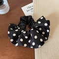 Vista dettagliata di un elegante elastico in seta a pois bianchi e neri su legno - Stile a Pois Neri