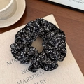 Texture dettagliata dell'elastico per capelli in tessuto a fiori nero e bianco sul libro - Nero Stampato