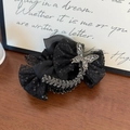 Detailed close-up of a black lace hair claw with sparkling sequins and a rhinestone butterfly - Black