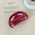 Detail of red cherry acetate hair claw clip with rhinestones on beige fabric backdrop - Red