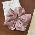 Detail view of pink silk satin scrunchie with Andrea woven label on wooden background - Pink
