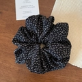 Detail view of the elegant black floral scrunchie on a rustic wooden tabletop - Black