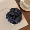Dettaglio di scrunchie retrò a quadri blu navy con perle bianche su sfondo di libri - Quadri Blu Notte