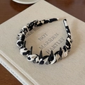 Detail of cow print fabric headband with black spikes and grey beads on a vintage book - Black