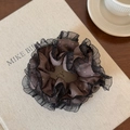 Detail of dark brown polka dot scrunchie with black mesh lace trim on book - Brown