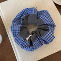 Gros plan d'un chouchou à carreaux bleus avec pendentif cœur doré sur un livre - Style Patchwork Gris Plaid Bleu Blanc / Gris
