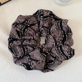 Dettaglio dell'elastico scrunchie nero con stampa paisley e trama plissettata elegante - Scrunchie Nero Paisley