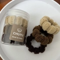 Macro view of high-elasticity earthy tone hair ties and plush scrunchies in a tray - Coffee Colors
