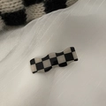 Detailopname van zwart-witte schaakbord haarklem op een witte getextureerde stoffen ondergrond - 1 Stuk / Golvend ruitjespatroon