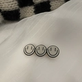Dettaglio macro di tre ciondoli a forma di smile grigi su fermaglio dorato - Faccina Sorridente Bianca