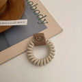 Nahaufnahme von cremefarbenem Telefonkabel-Haargummi mit braunem Smiley-Leder-Aufnäher - Gebrochenes Weiß
