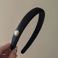 Dettaglio dell'elegante cerchietto in velluto nero con perla vintage e bordo dorato - Nero