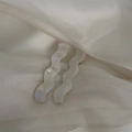Primer plano de horquillas onduladas nacaradas sobre un fondo de tela de seda blanca - Iridescent Pearly White Set