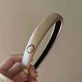 Dettaglio di un elegante cerchietto in raso champagne con perla vintage e montatura dorata - Bianco