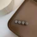 Dettaglio di quattro perline grigie lucide su un fermaglio per capelli minimalista - Grigio