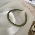 Dettaglio del cerchietto in pelle PU verde oliva con punte in metallo dorato su vassoio - Verde