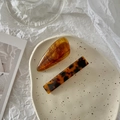 Close-up of elegant amber resin and tortoiseshell patterned hair clips on a ceramic tray - Amber Series