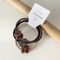 Dettaglio macro di tre elastici per capelli con ciondolo a quadrifoglio in acrilico leopardato - Stile Quadrifoglio